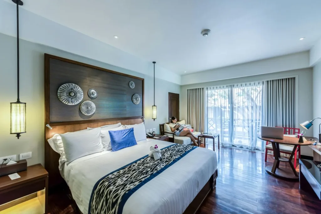 Modern bedroom interior in Houston, TX featuring tufted headboard, pendant lights, and balcony view