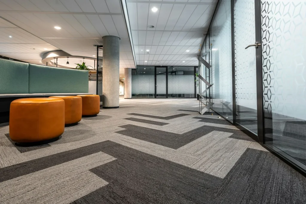 Interior Design Services in Sydney Modern office interior in Sydney with geometric carpet, glass partitions, and lounge seating